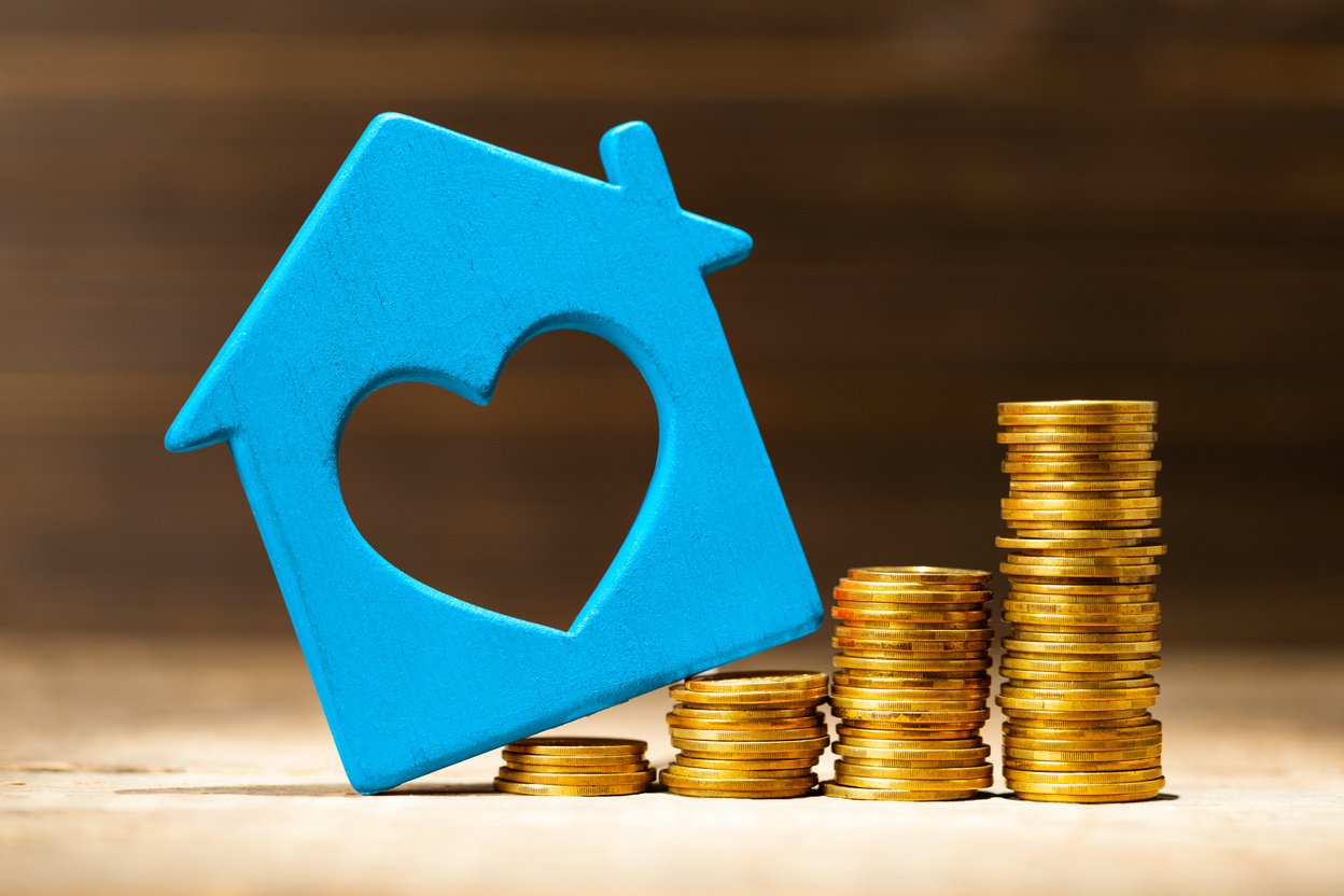 Blue House with Heart Shaped Hole and Stacks of Coins